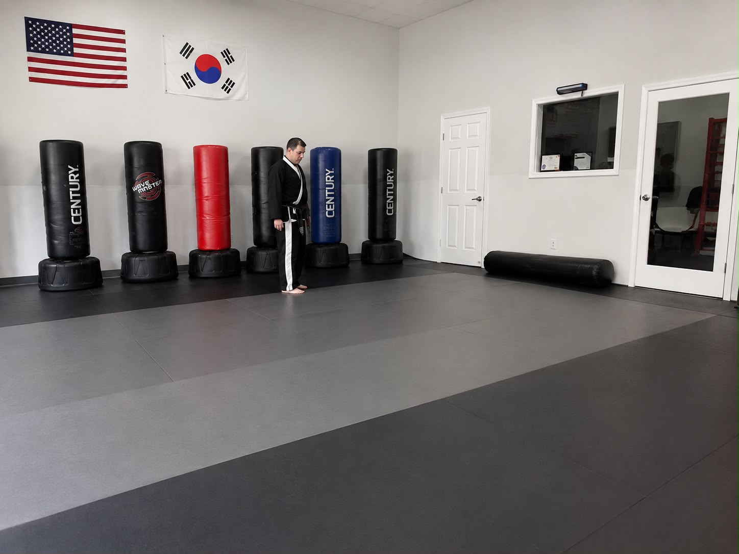 Empower Martial Arts instructor on the matted training floor with heavy bags in Lake Worth, FL