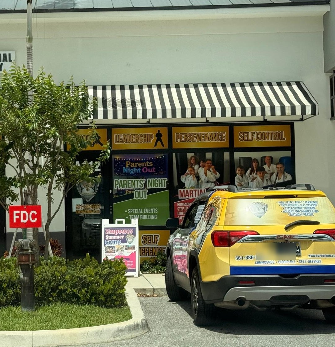 Empower Martial Arts Academy branded SUV parked at the storefront in Lake Worth FL, used for safe after school pickup from local schools