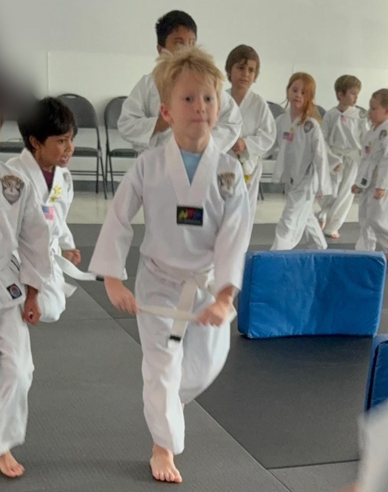 Young Empower Martial Arts Academy student stepping forward in a white uniform during an after school martial arts class in Lake Worth FL