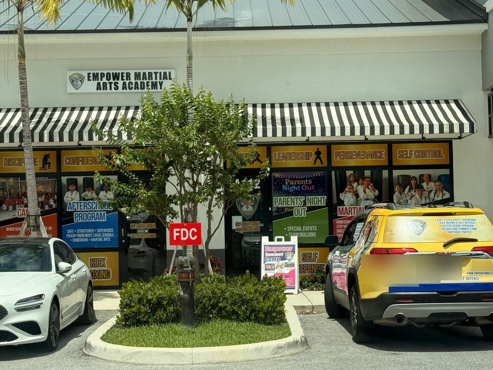 The full Empower Martial Arts Academy transportation fleet — yellow branded Ford Transit, silver passenger van, and white cargo van serving Lake Worth and Palm Springs after school pickup