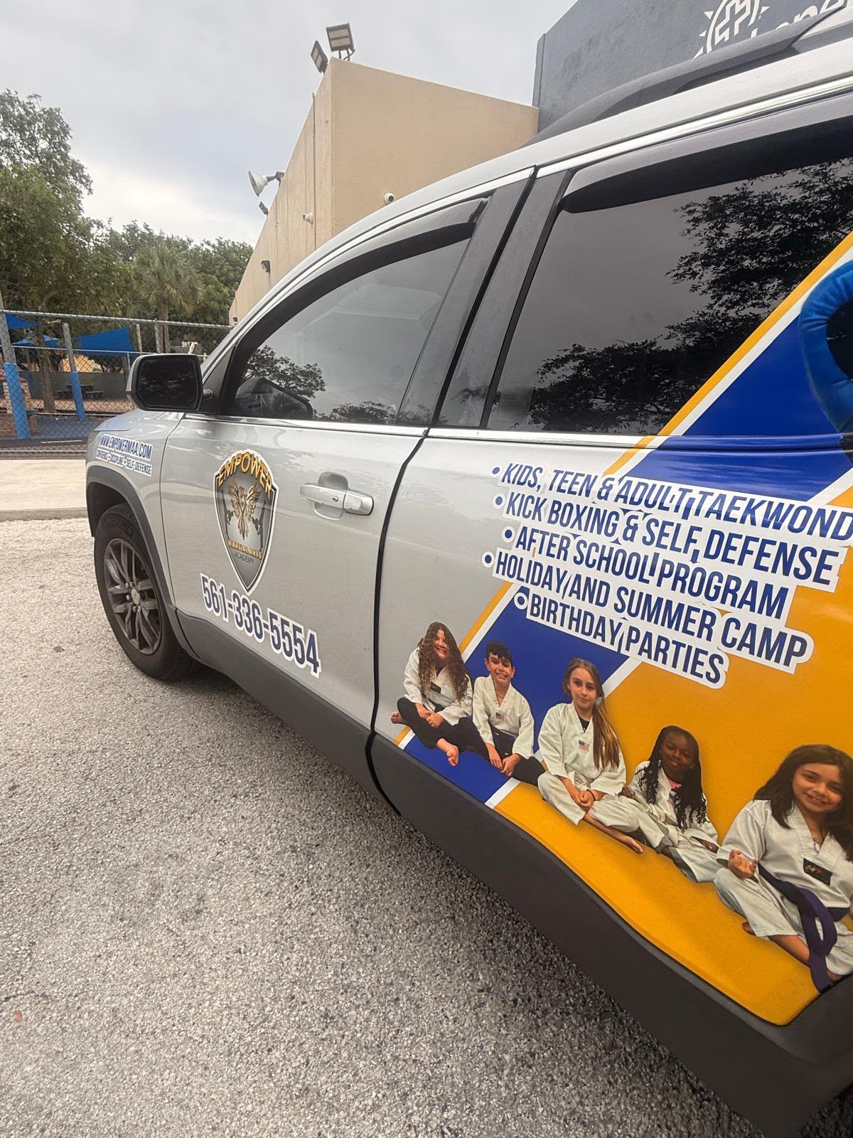Empower Martial Arts Academy children transportation vehicle #4 — silver SUV with academy wrap, phone 561-336-5554 and program list, for after school pickup in Lake Worth FL