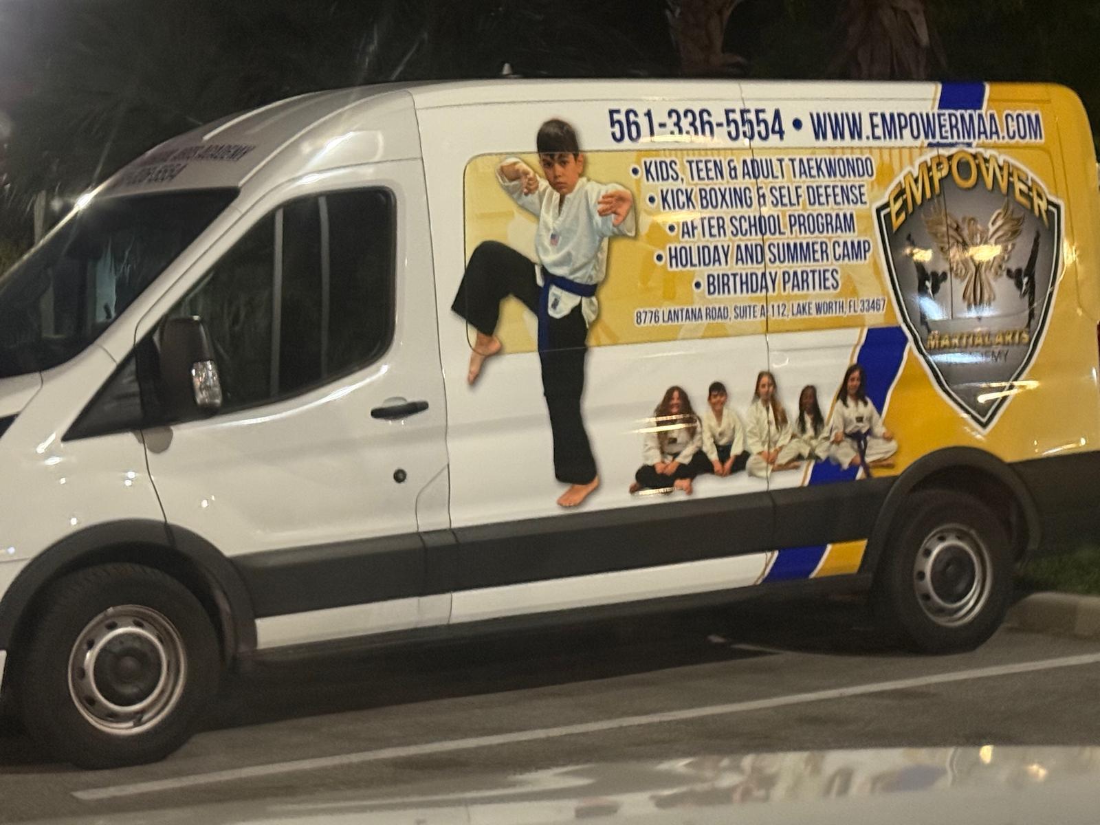 Empower Martial Arts Academy children transportation van #1 — white Ford Transit with yellow branded wrap, phone 561-336-5554 and program list, for safe after school pickup in Lake Worth FL