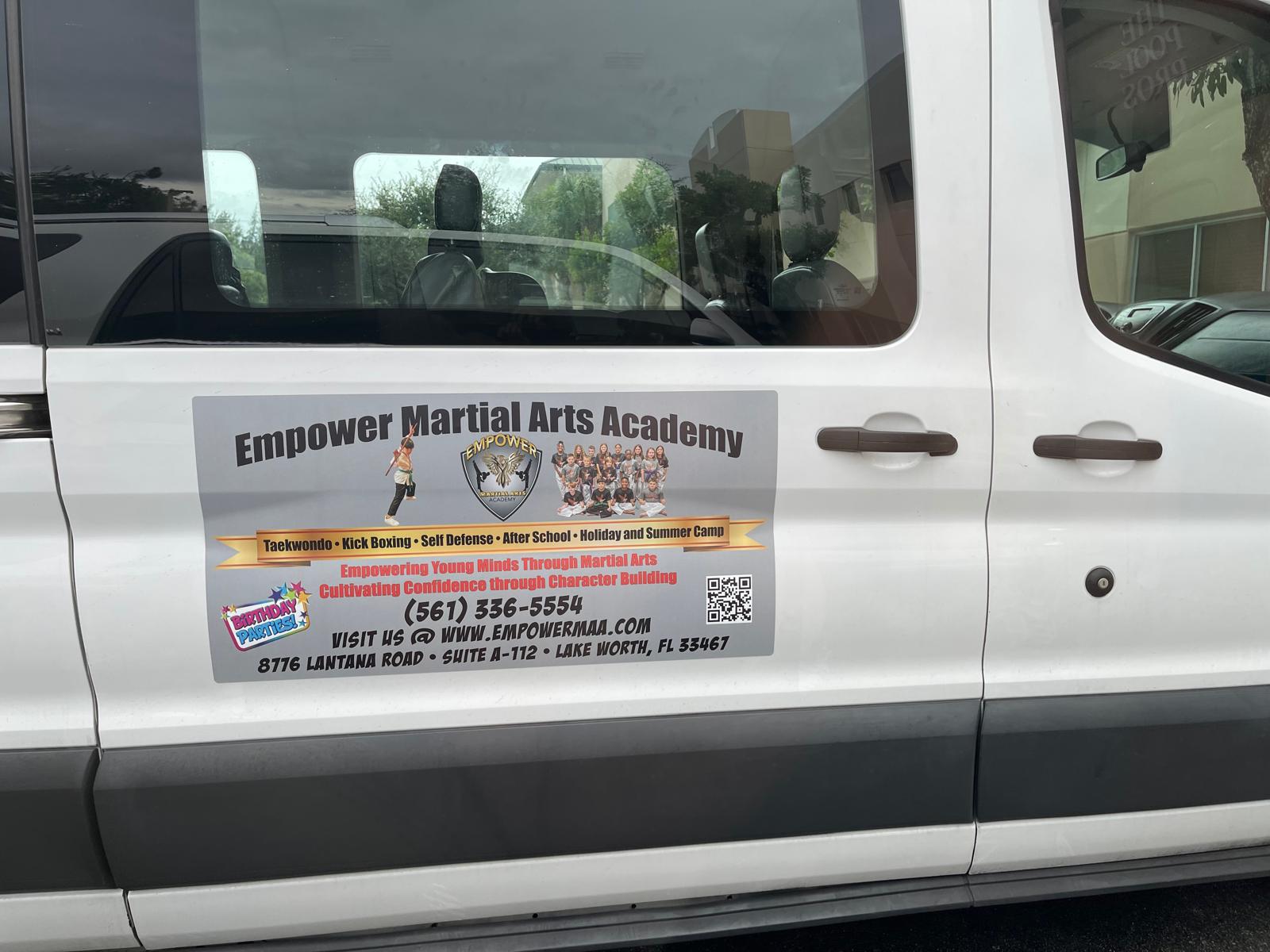 Empower Martial Arts Academy children transportation van #6 — white Ford Transit passenger van with side door magnet showing academy branding, birthday parties, QR code and 561-336-5554 phone number, for after school pickup in Lake Worth FL