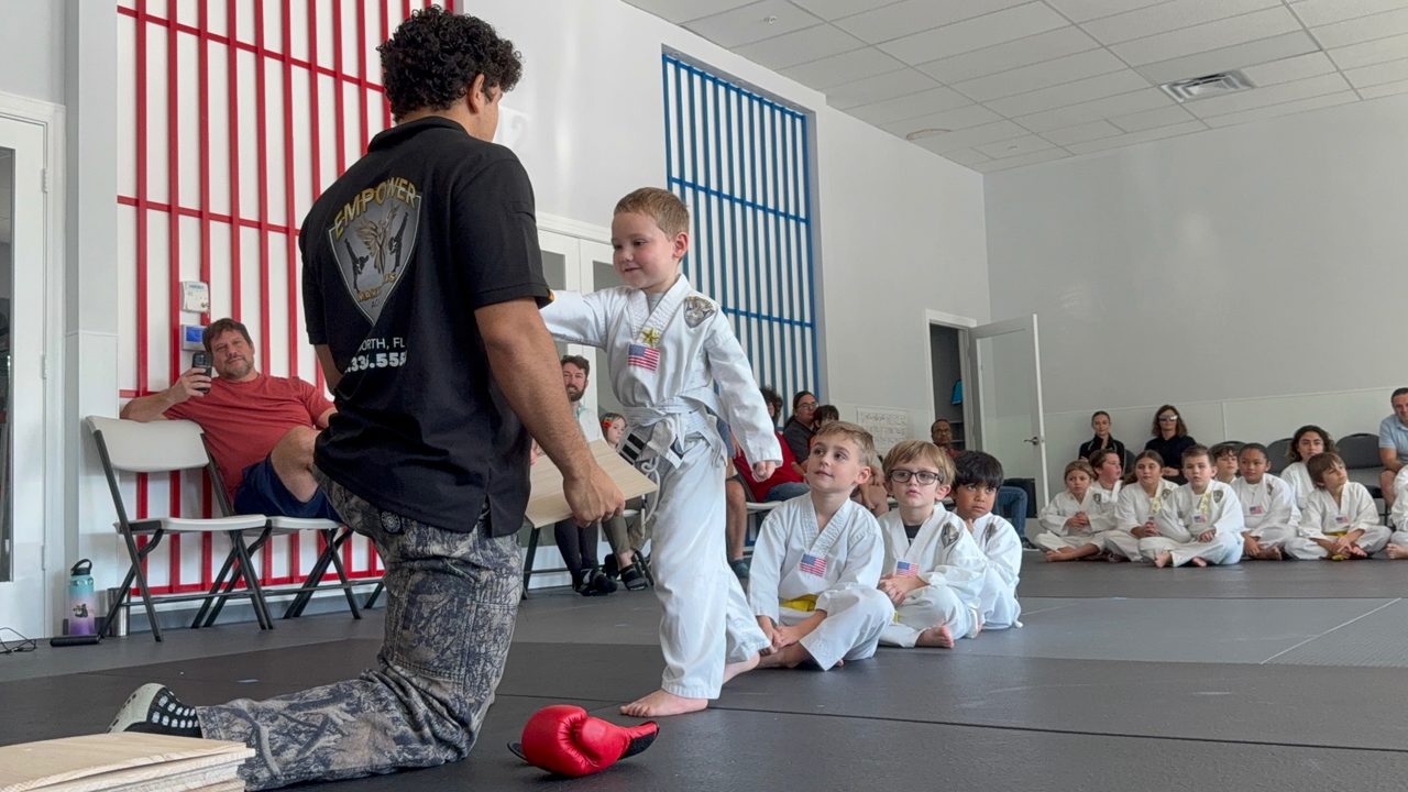 Young Little Ninjas student breaking a board with Empower Martial Arts instructor during a Lake Worth, FL kids martial arts class